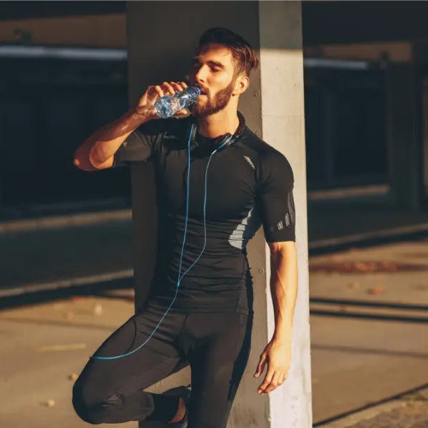 Man in athletic wear drinking water outdoors